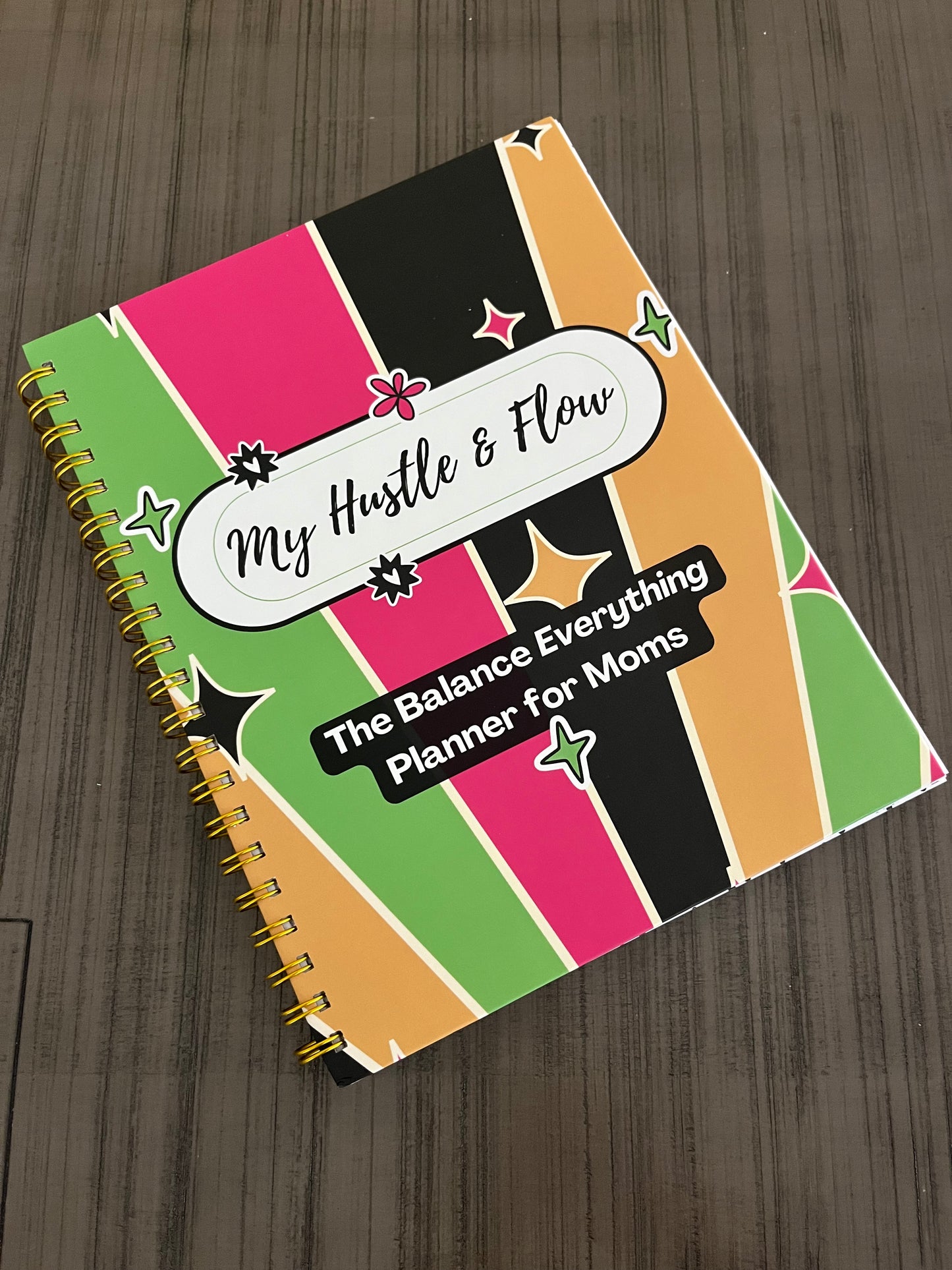 Hustle & Flow Planner displayed on a table featuring bold, feminine branding designed for busy moms and creators.